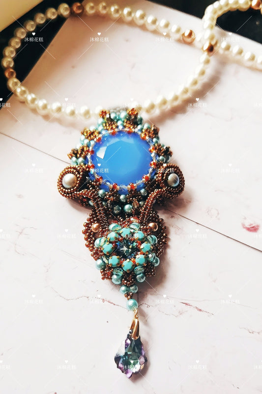 This handcrafted statement piece features a celestial-inspired design. Measuring 11×4cm, it combines glass imitation pearls, delicate glazed seed beads, and Swarovski crystals to create a stunning comet-themed pendant. The upper section is a refined pearl necklace, while the blue accents in the pendant symbolize the sky, adding a touch of elegance and meaning to the design.